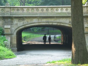 Couple walking under arched bridge in Central Park
